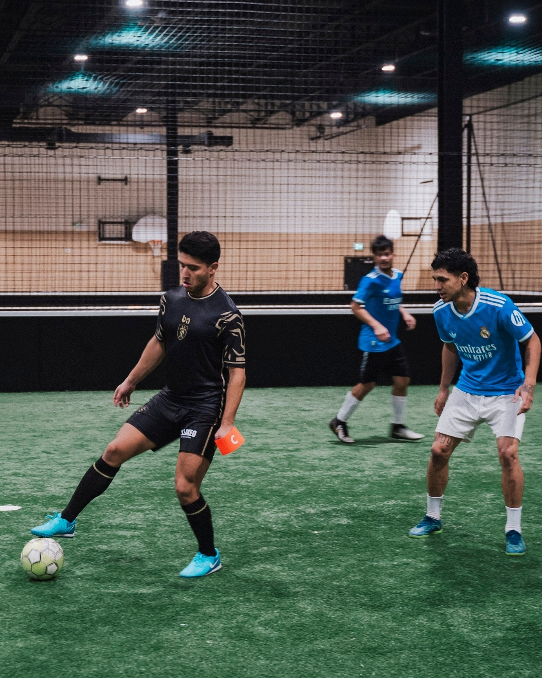 ba Gear custom soccer uniforms in play, player controlling ball on indoor field wearing black kit