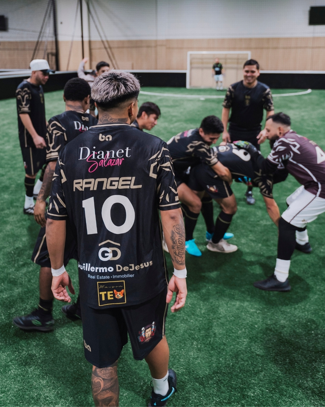 ba Gear custom soccer uniforms, team huddle on indoor field wearing black jerseys before match